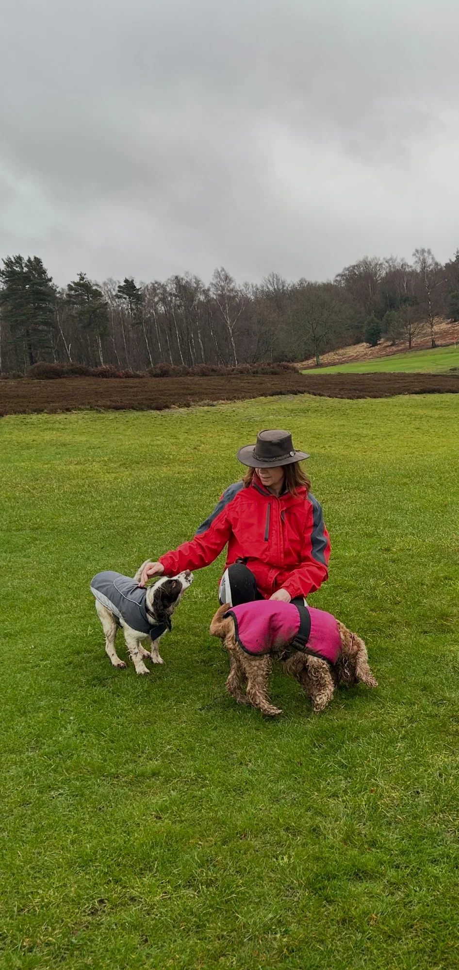 Joanne sitting with dogs in open countryside